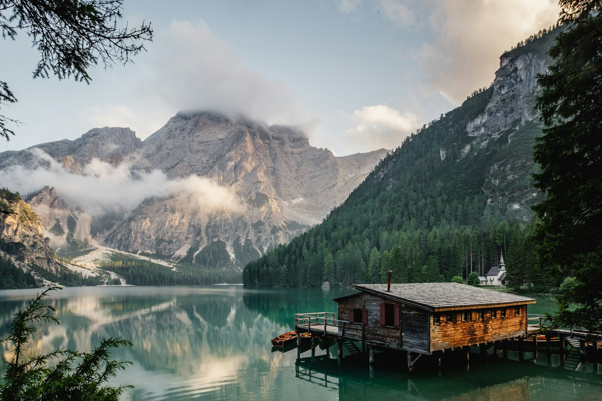 A timber cabin beside a turquoise mountain lake, surrounded by forest